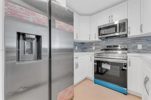 a kitchen with stainless steel appliances granite countertop a stove a microwave and a refrigerator