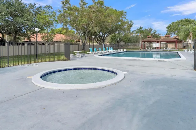 a view of a swimming pool with a yard and palm trees