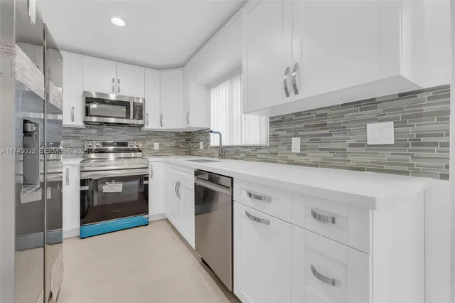 a kitchen with stainless steel appliances granite countertop white cabinets and a stove top oven