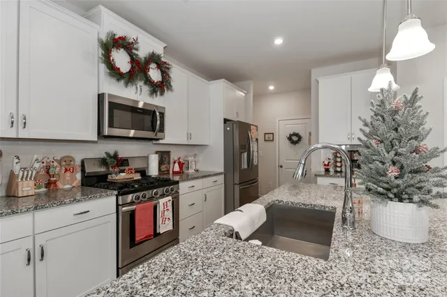 a kitchen with stainless steel appliances granite countertop a sink a stove a microwave a refrigerator and cabinets