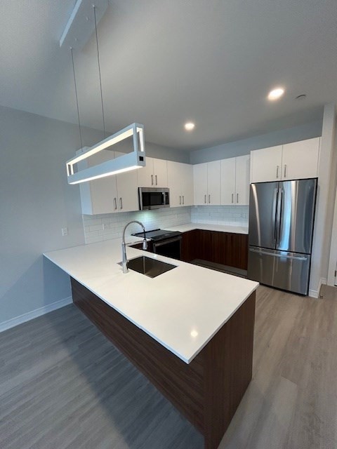 148 Old Post Road, Unit 216 Sharon, MA 02067 - Photo 3 of 22 a kitchen with stainless steel appliances a white stove top oven a sink and a refrigerator