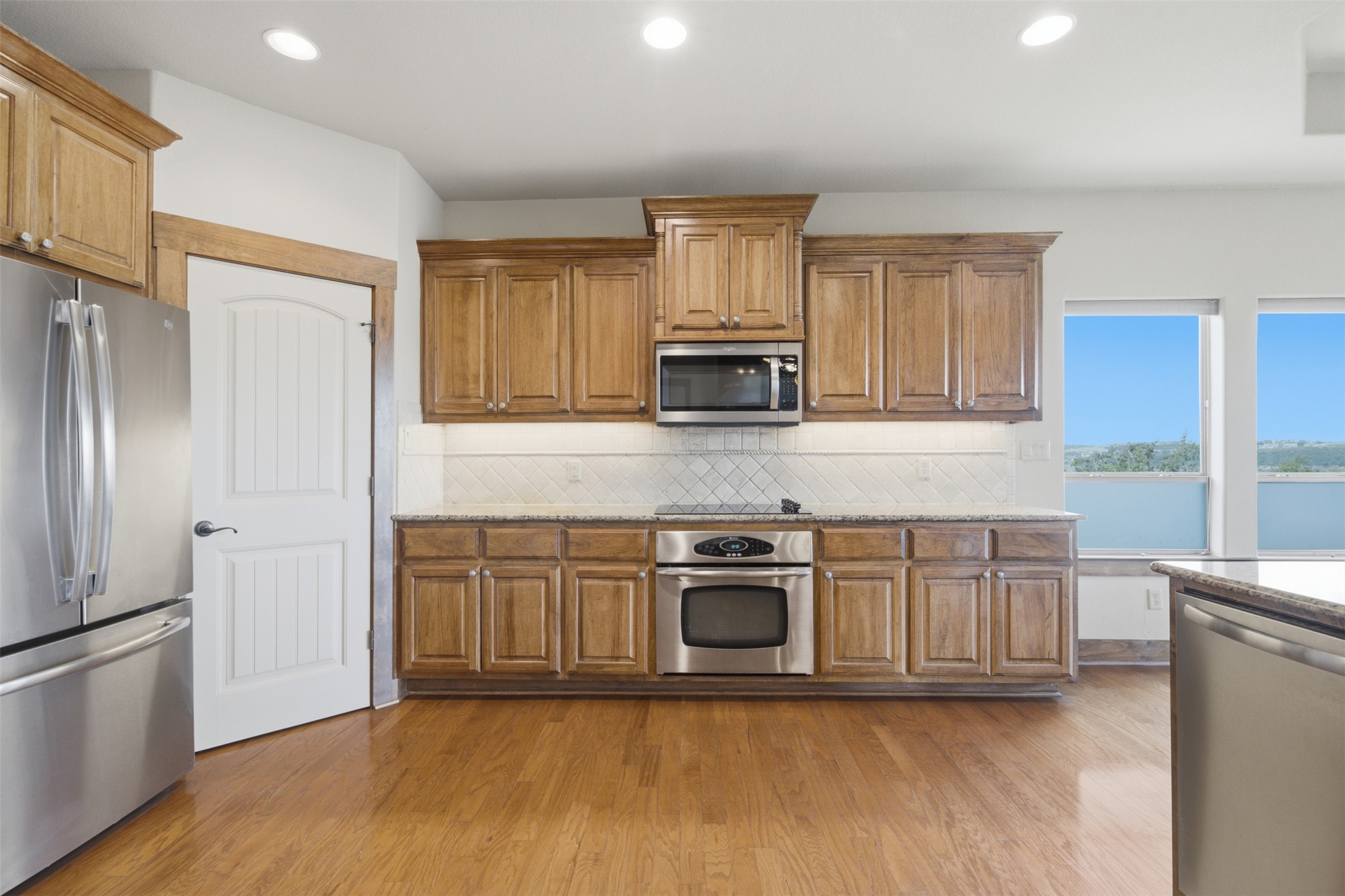 700 Augusta Circle Point Venture, TX 78645 - Photo 5 of 35 A sleek kitchen features modern stainless steel appliances set against rich wood cabinetry and gleaming hardwood flooring.