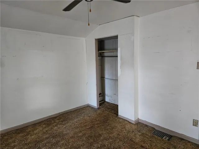 an empty room with closet and a ceiling fan