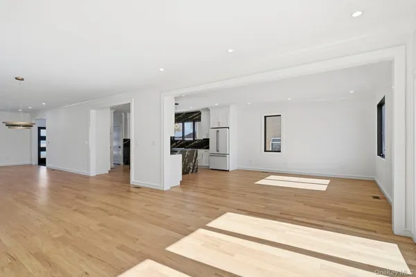 a view of an empty room with kitchen and window
