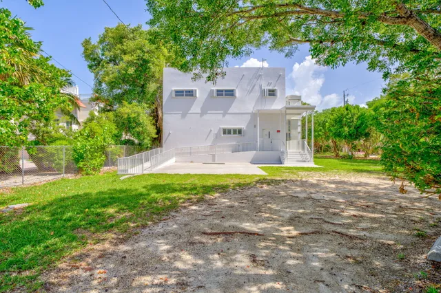 a view of a house with a yard and a large tree