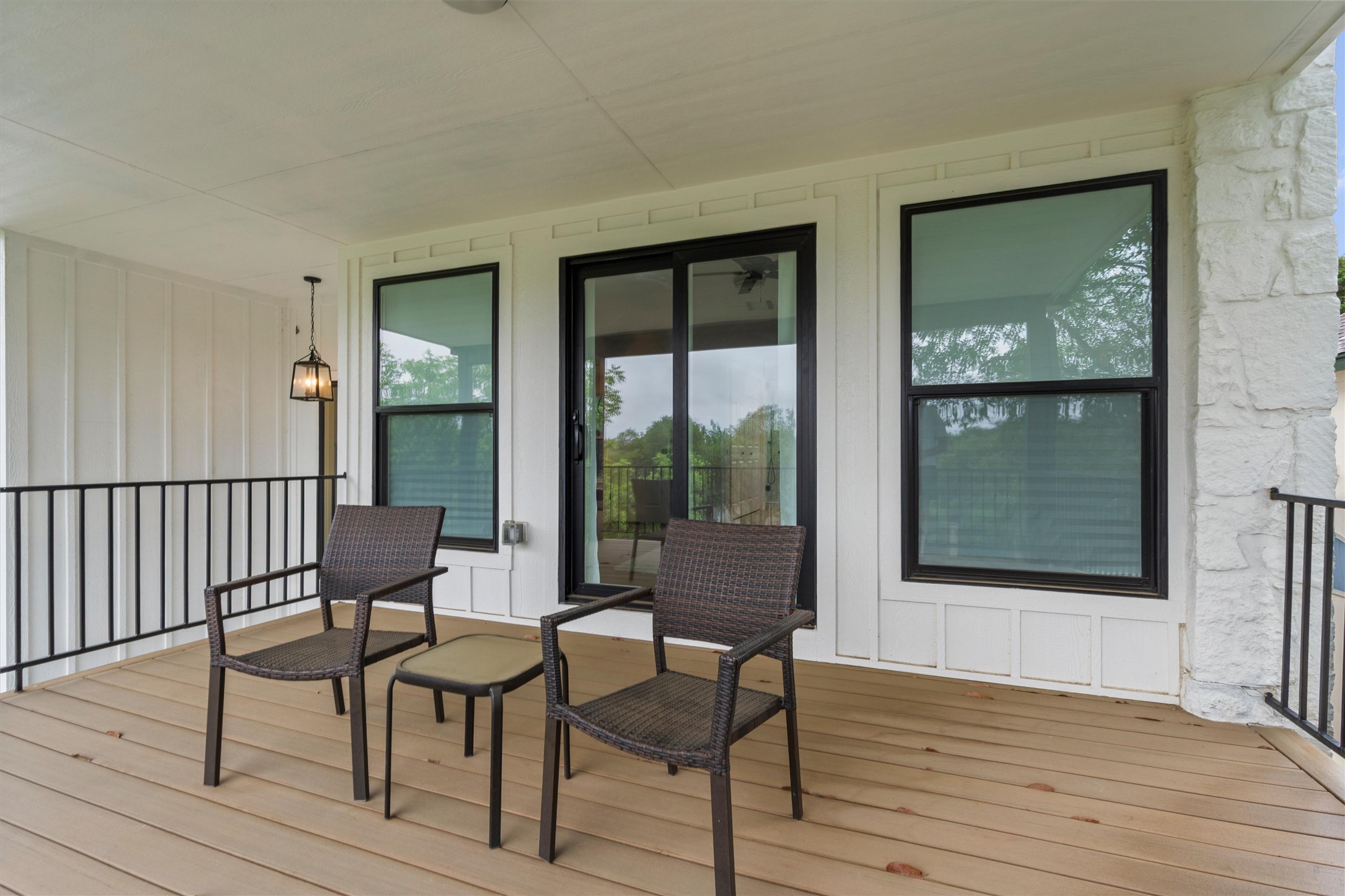307 Hurst Creek Road Austin, TX 78734 - Photo 27 of 40 Covered outdoor patio featuring composite decking, a sliding glass door, two large windows with black frames, and a black metal railing