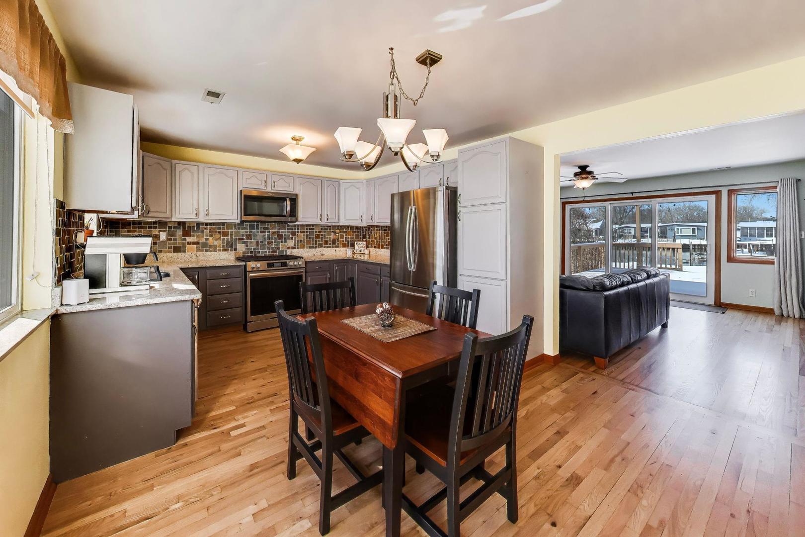 37464 North Terrace Lane Spring Grove, IL 60081 - Photo 6 of 40 a kitchen with stainless steel appliances granite countertop a stove a refrigerator a kitchen island a dining table and chairs with wooden floor