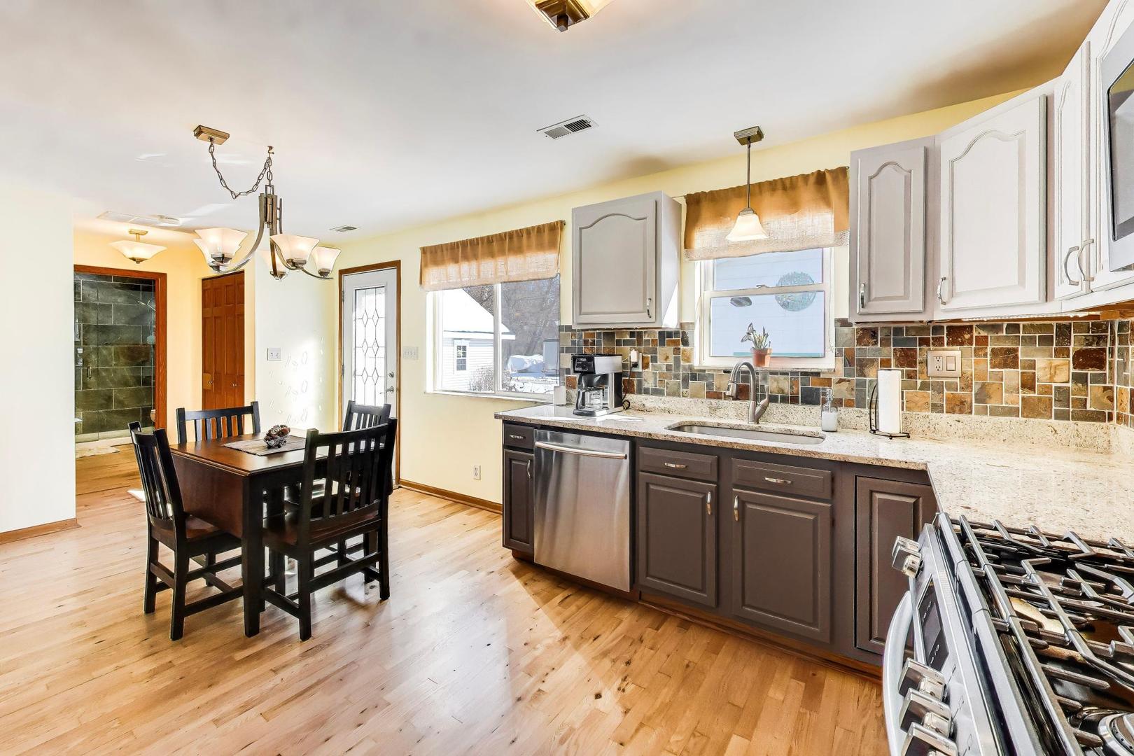 37464 North Terrace Lane Spring Grove, IL 60081 - Photo 9 of 40 a kitchen with stainless steel appliances granite countertop wooden floor a dining table and chairs