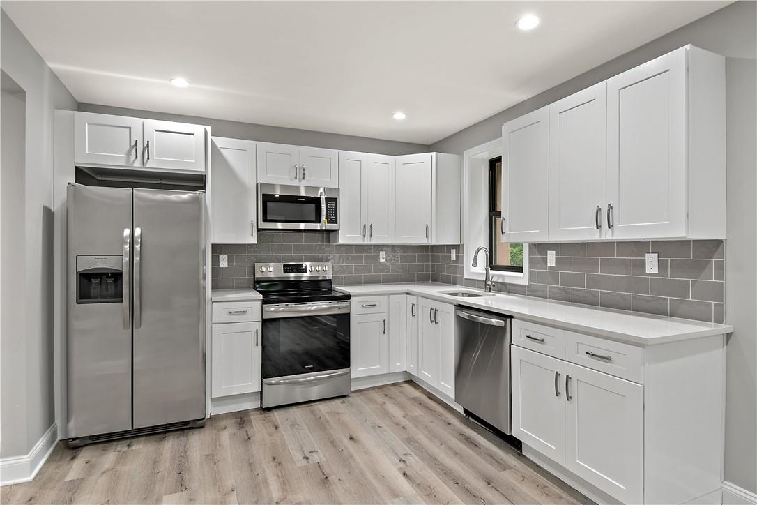a kitchen with stainless steel appliances granite countertop a stove top oven a refrigerator and white cabinets