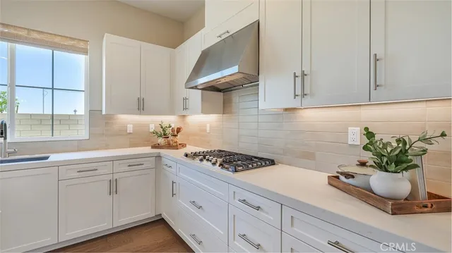 a kitchen with white cabinets and a window