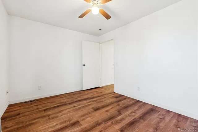 an empty room with a ceiling fan and wooden floor