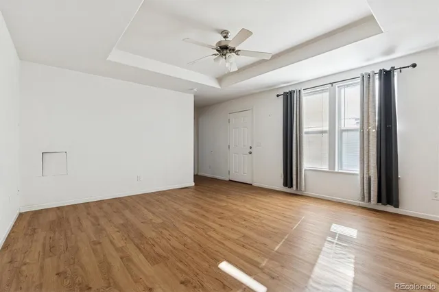 a view of an empty room with a window and wooden floor
