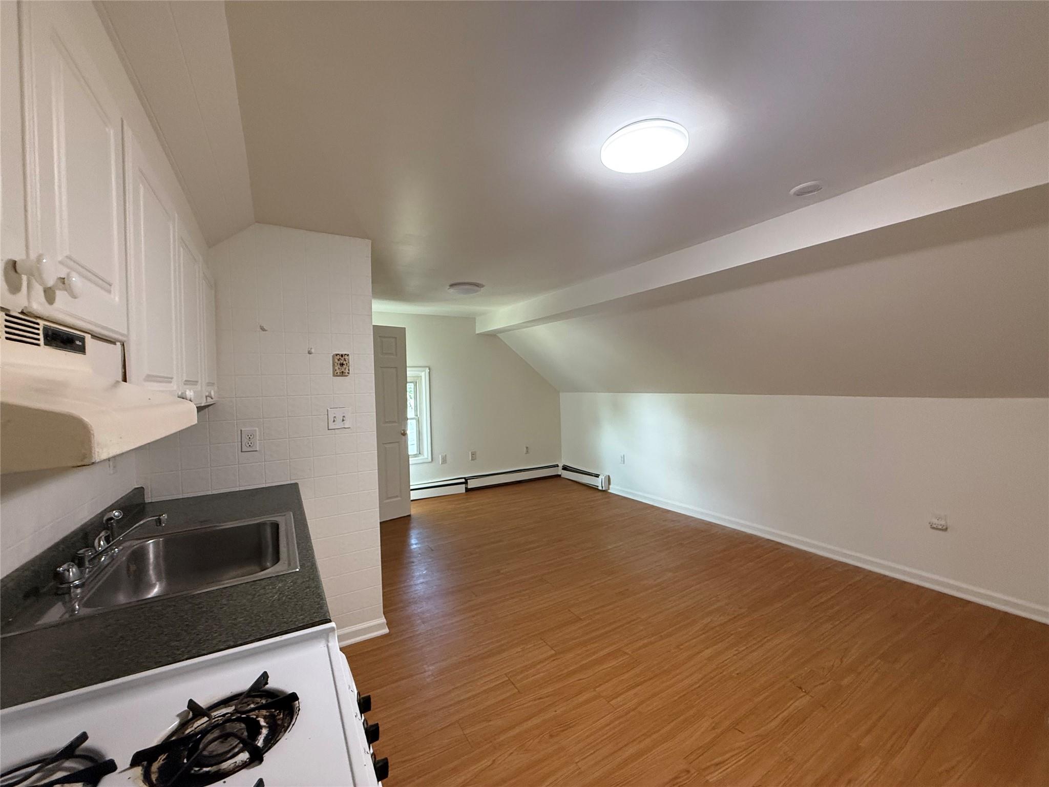 8 Harrison Street, Unit 3 Poughkeepsie, NY 12601 - Photo 3 of 6 Kitchen with vaulted ceiling, wood finished floors, white cabinets, dark countertops, and stove