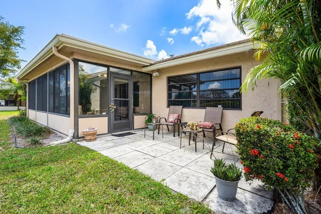 a view of a patio with table and chairs potted plants and a palm tree