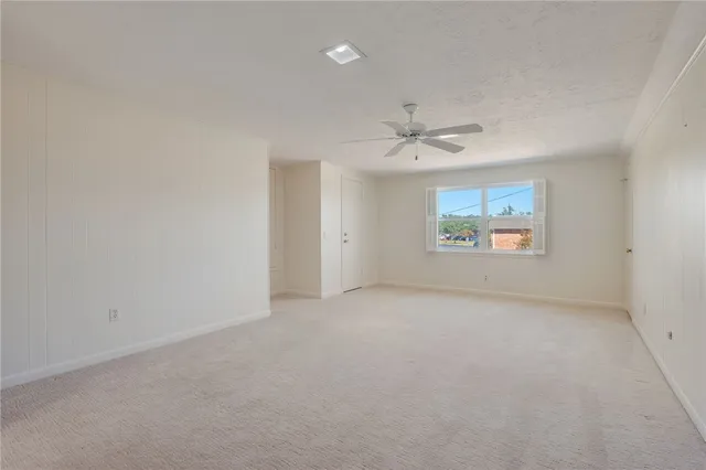 an empty room with a ceiling fan and window