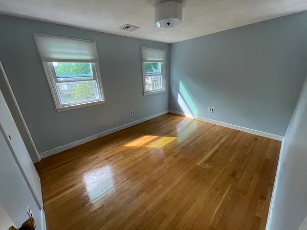 a view of empty room with window and wooden floor