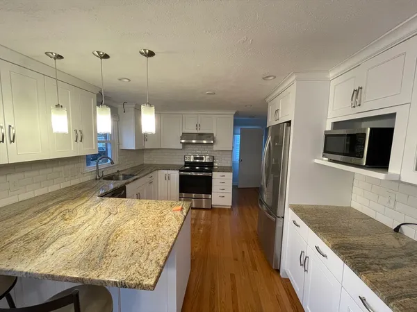 a large kitchen with kitchen island a large counter top space a sink stainless steel appliances and cabinets
