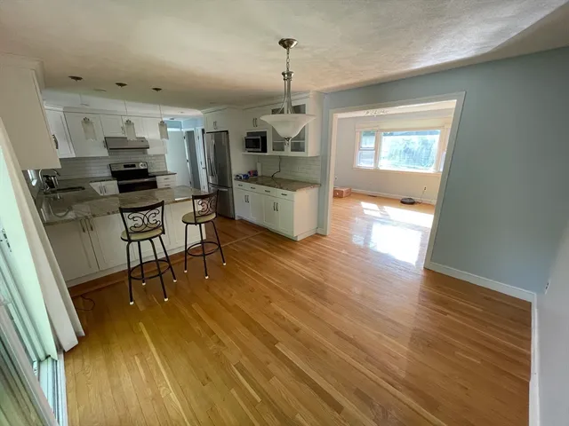 a kitchen with stainless steel appliances kitchen island granite countertop a table chairs and a refrigerator