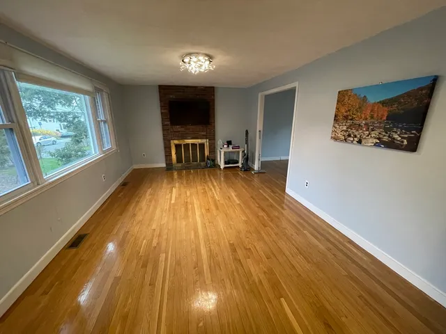 a view of a room with wooden floor fridge and a window