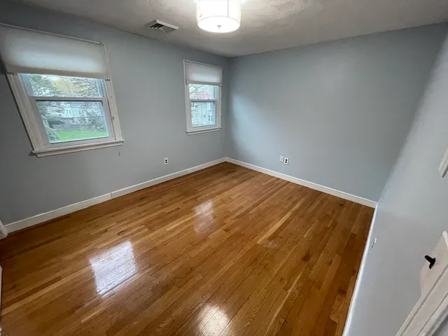 a view of empty room with window and wooden floor