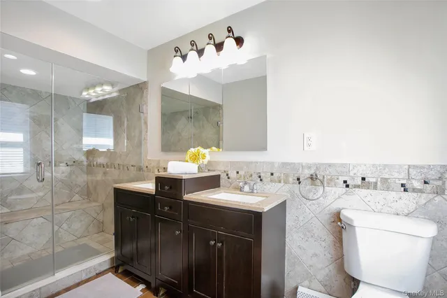 a bathroom with a double vanity sink mirror and toilet