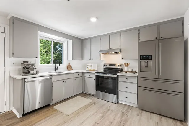 a kitchen with granite countertop appliances a sink cabinets and a window