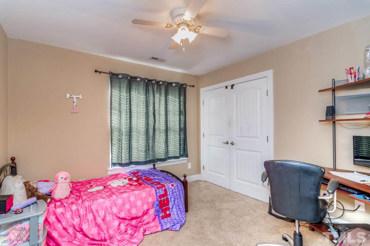 210 Orkney Road Stem, NC 27581 - Photo 18 of 26 a bedroom with a bed and a chandelier