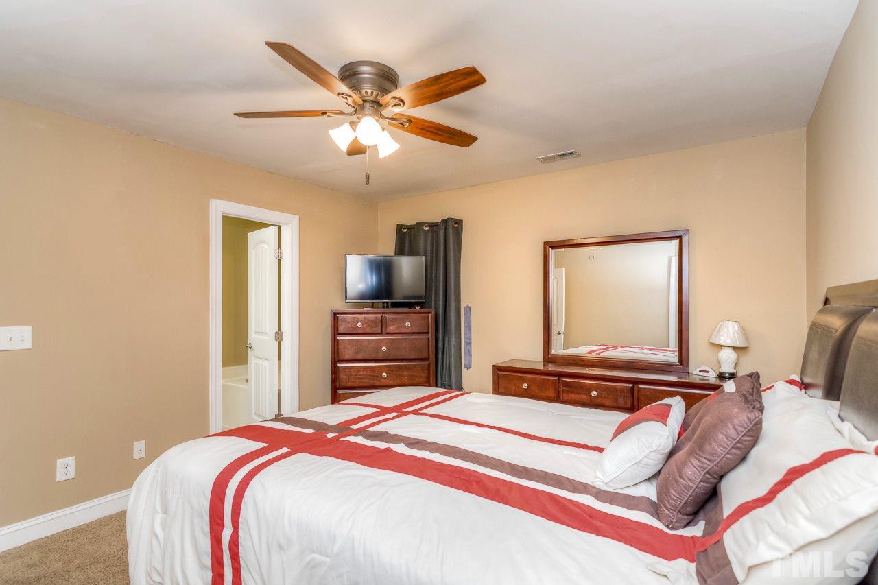 210 Orkney Road Stem, NC 27581 - Photo 22 of 26 a bedroom with a bed and a chandelier
