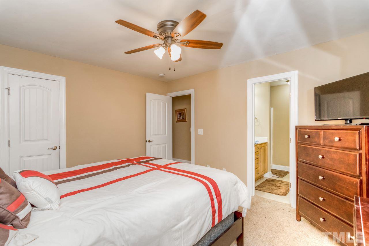 210 Orkney Road Stem, NC 27581 - Photo 23 of 26 a bedroom with a bed and a chandelier