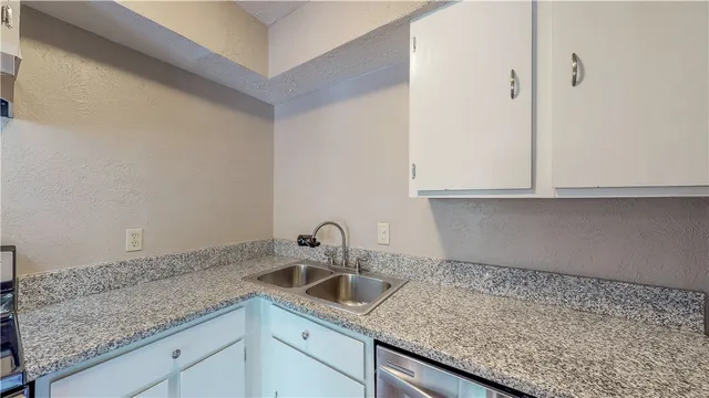 a kitchen with granite countertop white cabinets and a sink