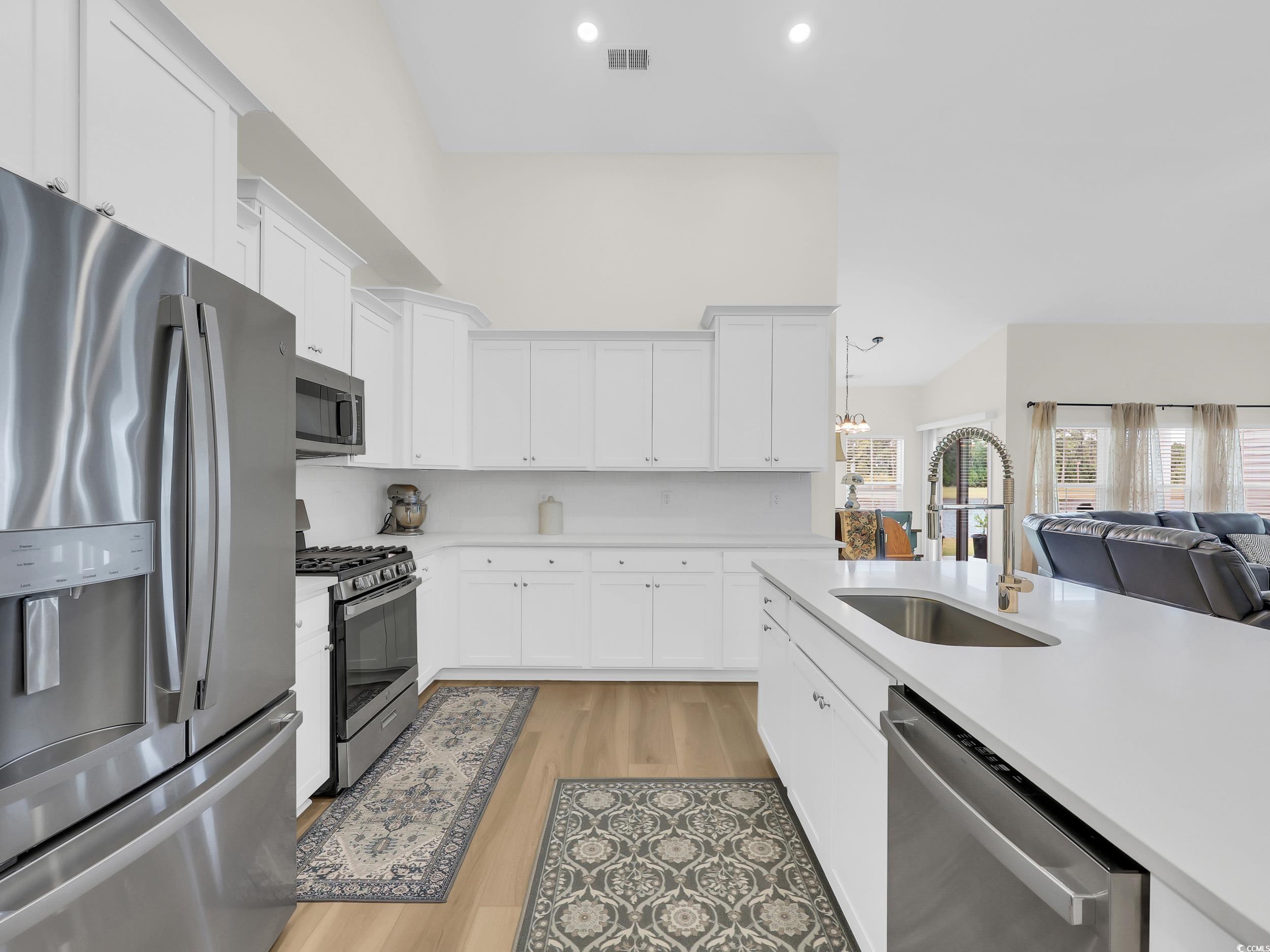 322 Augusta Grn Way Myrtle Beach, SC 29579 - Photo 34 of 34 Kitchen featuring stainless steel appliances, open floor plan, white cabinetry, recessed lighting, and a towering ceiling
