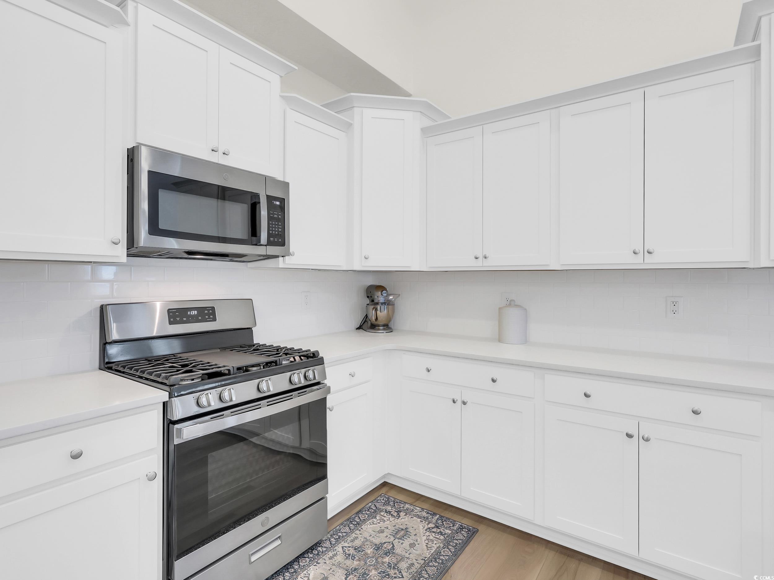 322 Augusta Grn Way Myrtle Beach, SC 29579 - Photo 11 of 34 Kitchen featuring stainless steel appliances, decorative backsplash, white cabinets, and light wood-type flooring