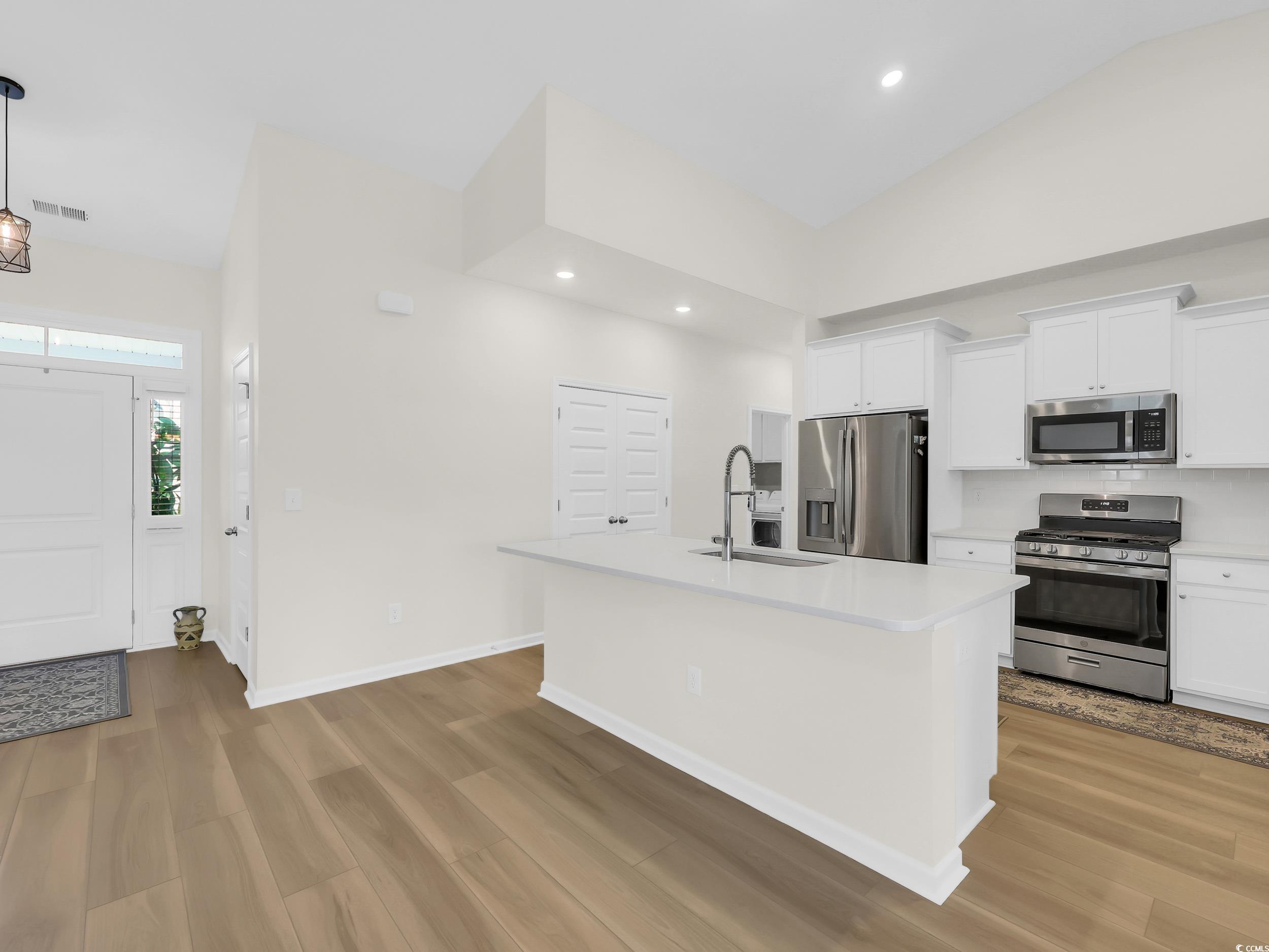322 Augusta Grn Way Myrtle Beach, SC 29579 - Photo 12 of 34 Kitchen with appliances with stainless steel finishes, white cabinetry, a center island with sink, light wood-style flooring, and recessed lighting