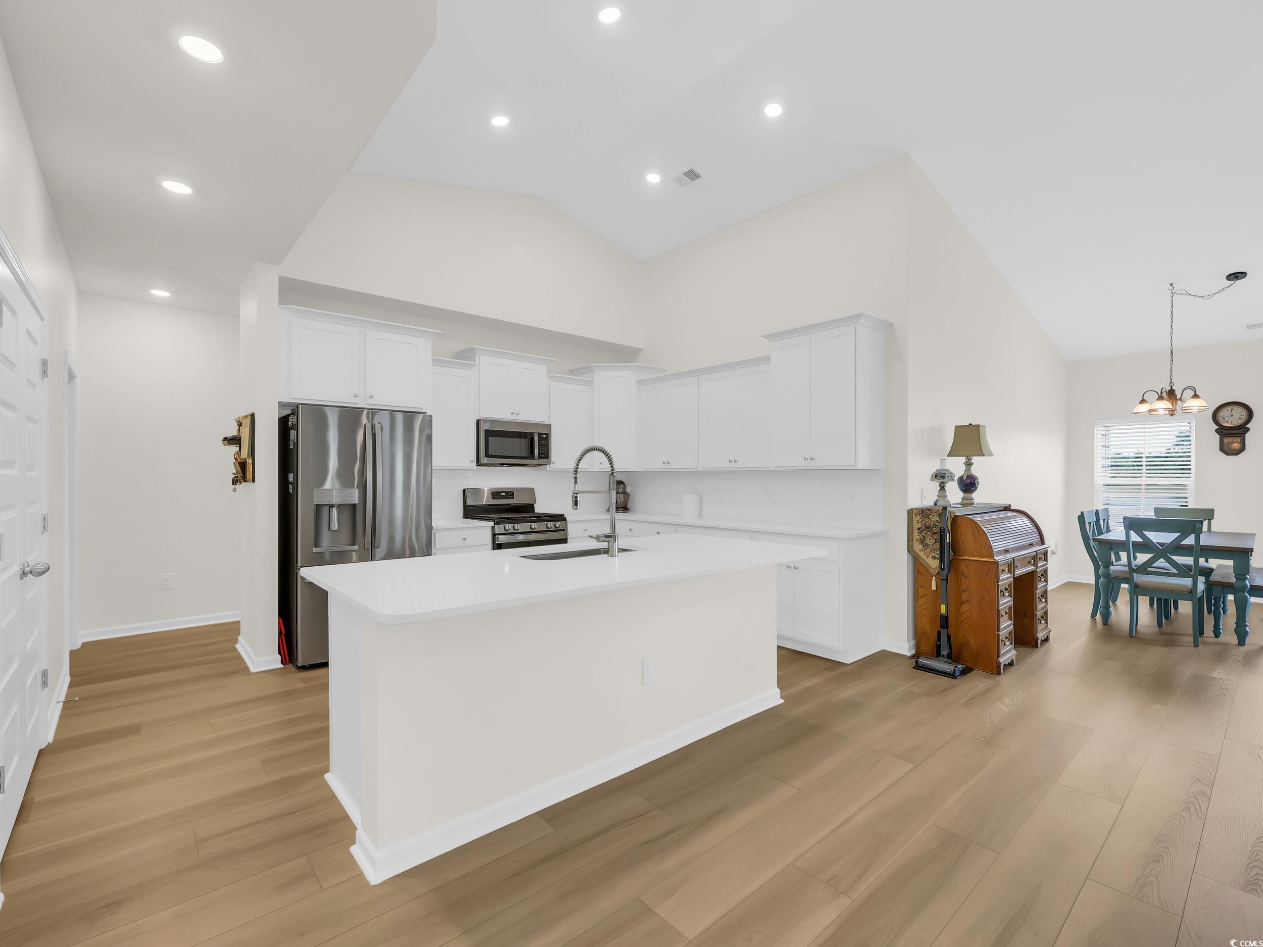 322 Augusta Grn Way Myrtle Beach, SC 29579 - Photo 10 of 34 Kitchen featuring appliances with stainless steel finishes, white cabinets, light wood-style flooring, a kitchen island with sink, and recessed lighting