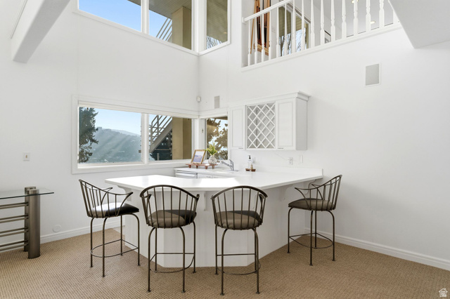 1878 East Ridge Point Drive Bountiful, UT 84010 - Photo 44 of 92 Dining space featuring healthy amount of natural light, light colored carpet, a high ceiling, and wet bar