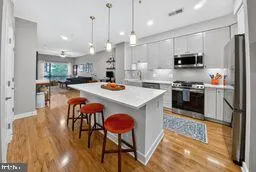 a kitchen with stainless steel appliances granite countertop a stove a refrigerator a oven a sink a dining table and chairs with wooden floor