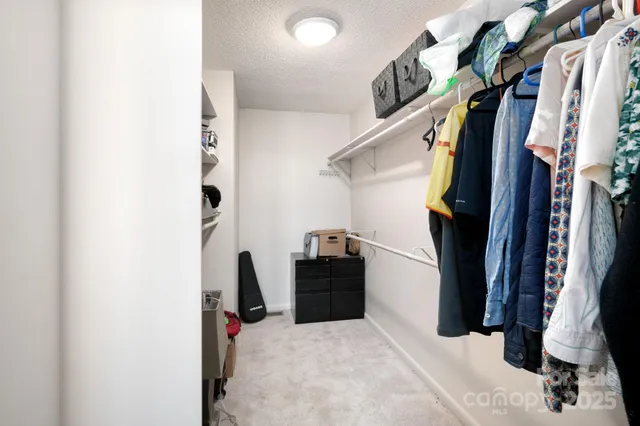 a view of walk in closet with clothes and shoes