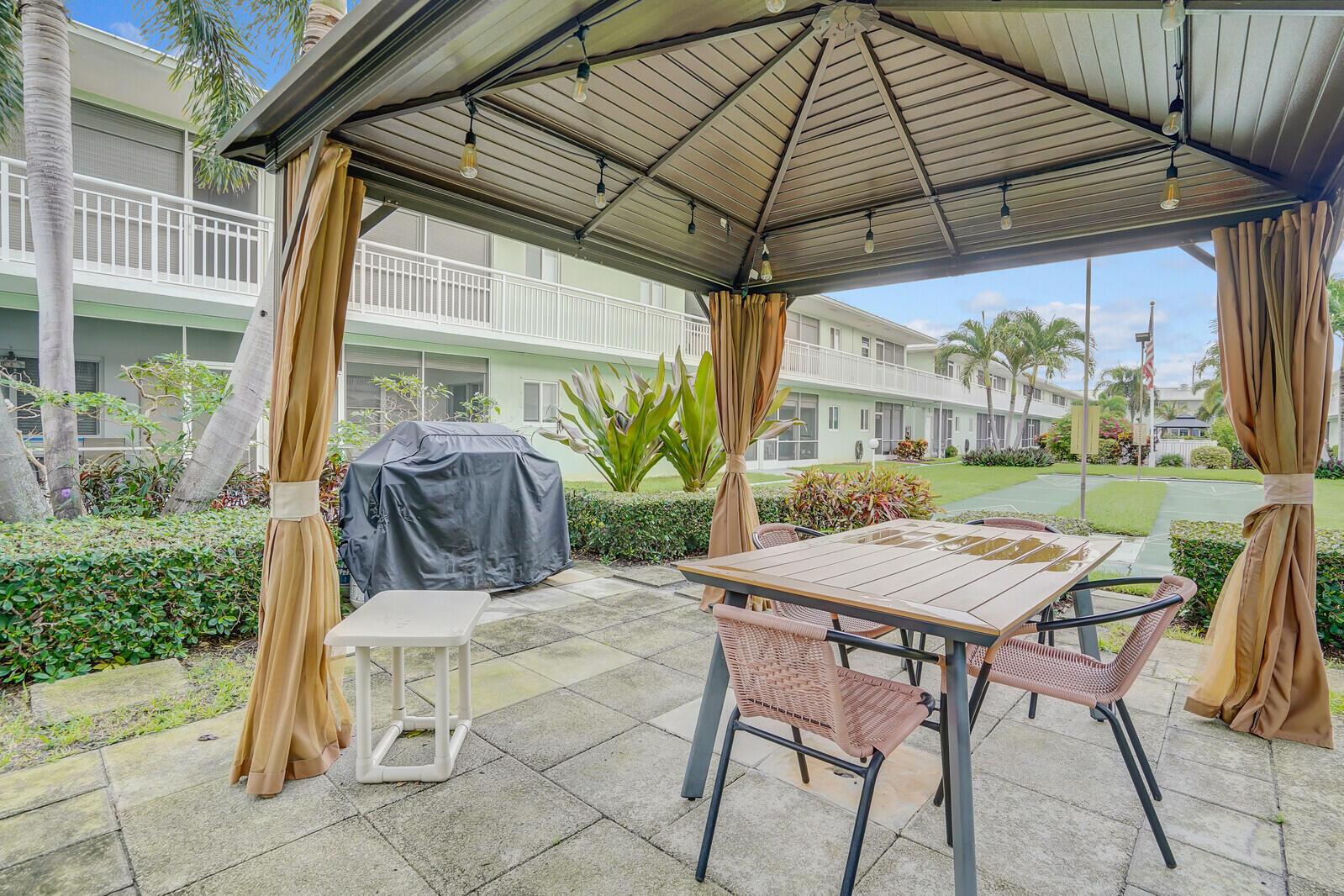 2100 Northeast 38th Street, Unit 111 Lighthouse Point, FL 33064 - Photo 18 of 25 a view of a patio with a table and chairs under an umbrella