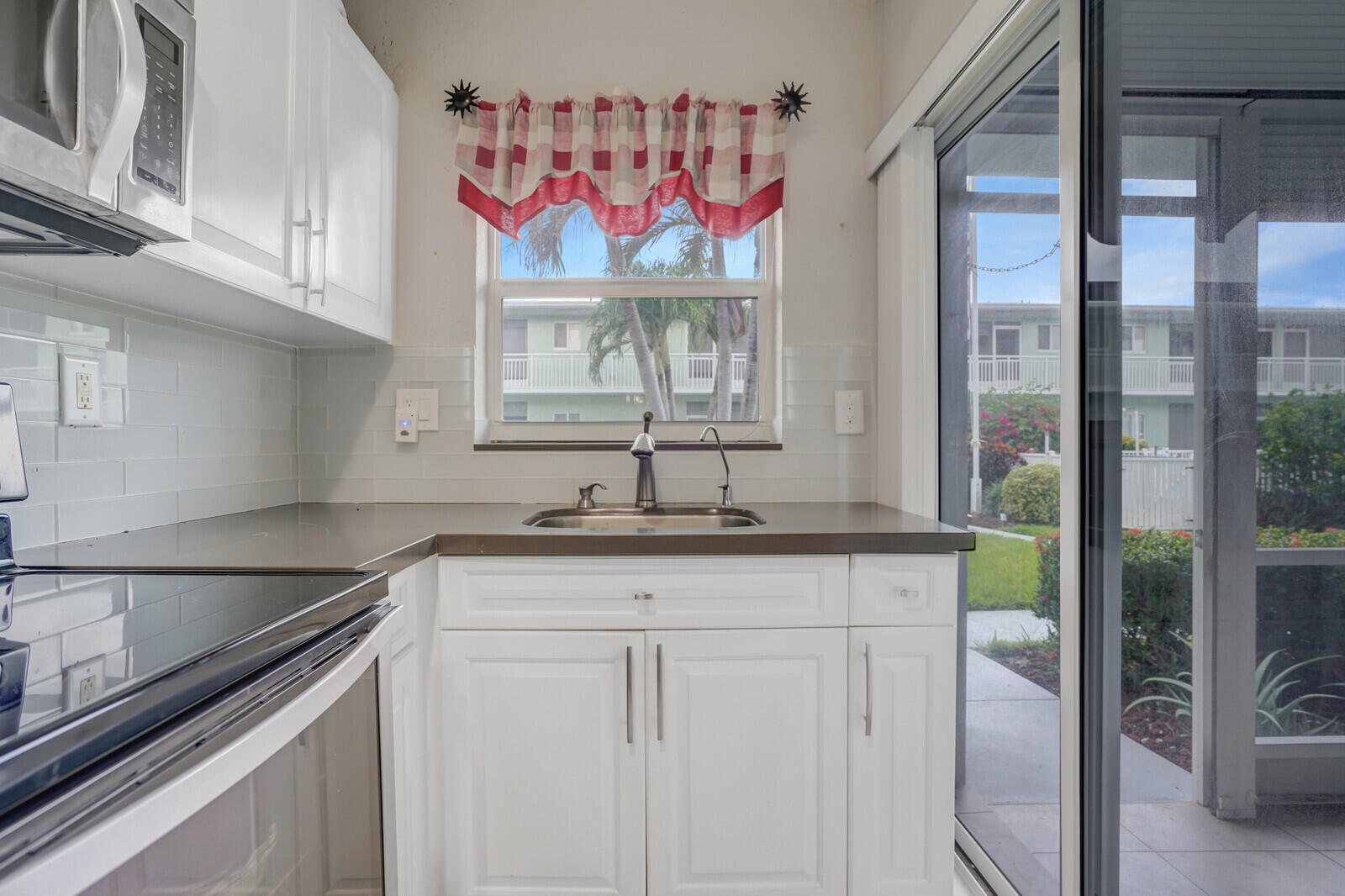2100 Northeast 38th Street, Unit 111 Lighthouse Point, FL 33064 - Photo 10 of 25 a kitchen with stainless steel appliances a sink and cabinets