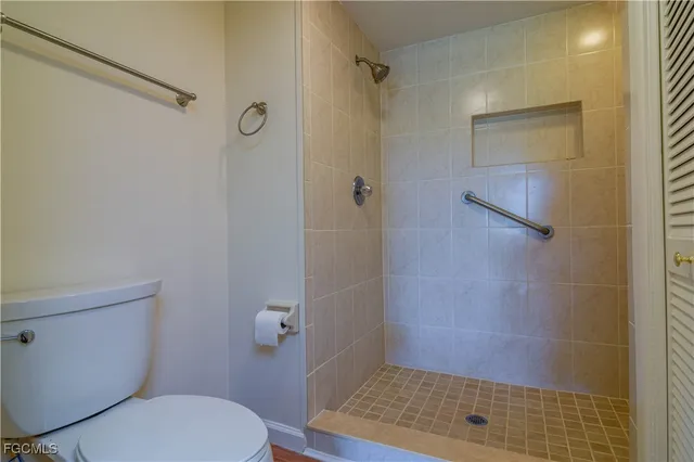 an empty room with wooden floor closet and windows