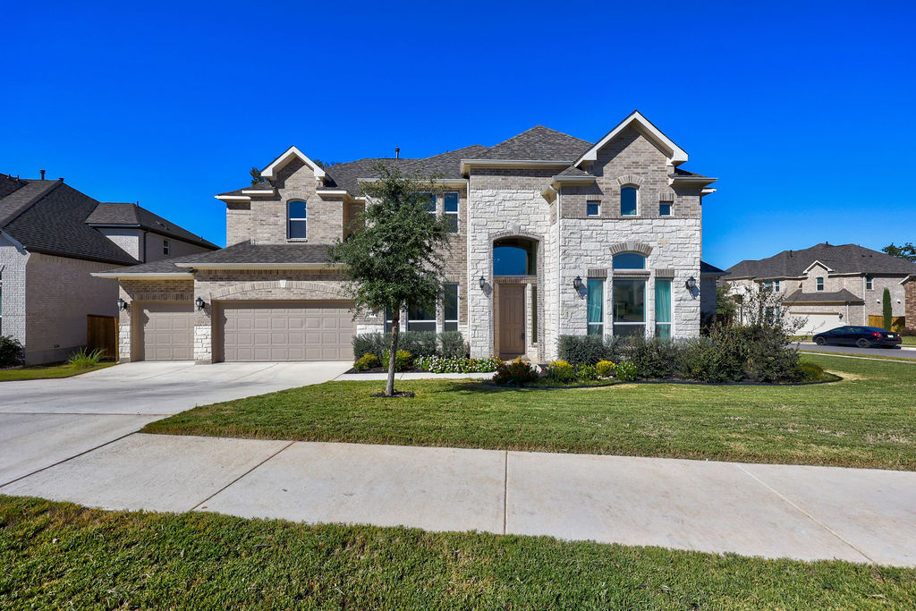 351 Pigeon River Road Kyle, TX 78640 - Photo 1 of 40 French provincial home with driveway, a front lawn, stone siding, a garage, and brick siding