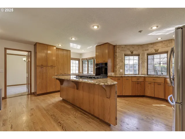 a large kitchen with a large counter top a sink stainless steel appliances and cabinets