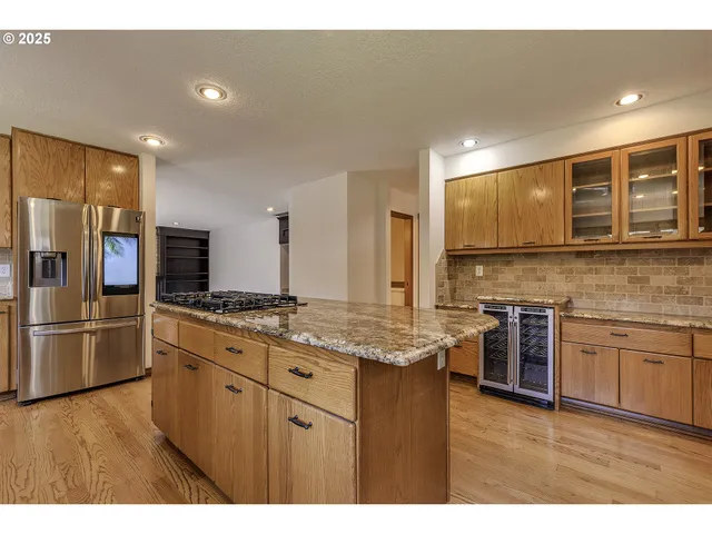 a kitchen with stainless steel appliances granite countertop a stove top oven a sink dishwasher a refrigerator and a microwave oven with wooden floor
