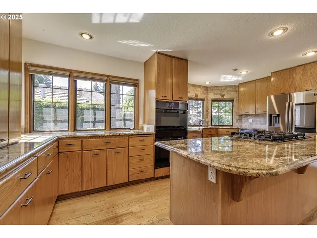 a kitchen with stainless steel appliances granite countertop a sink counter space cabinets and a large window