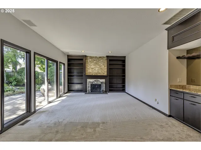 a view of an empty room with a fireplace and a window