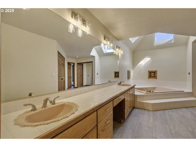 a bathroom with a granite countertop sink a large mirror and bathtub