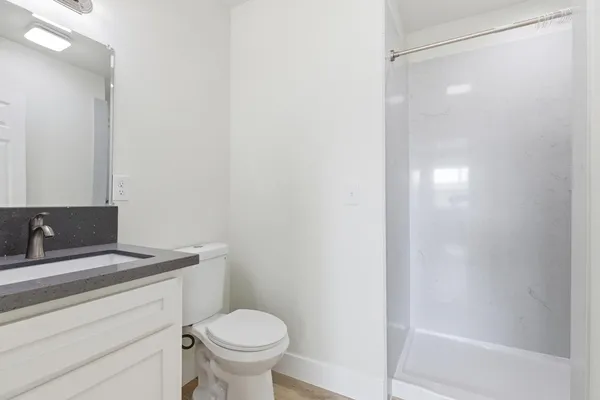 a bathroom with a granite countertop sink toilet and shower