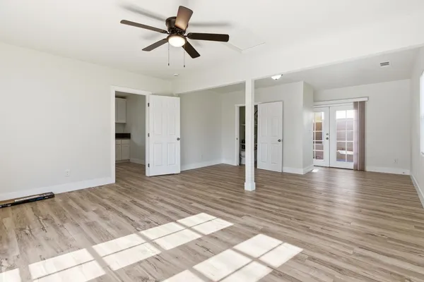a view of empty room with wooden floor and ceiling fan