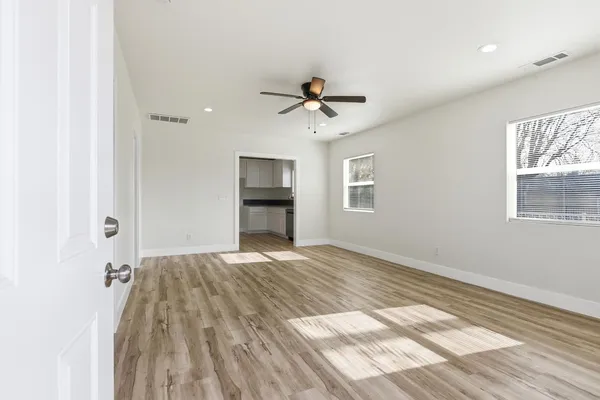 a view of empty room with wooden floor and fan