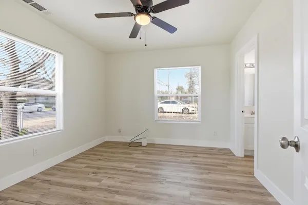 a view of an empty room with a window and wooden floor